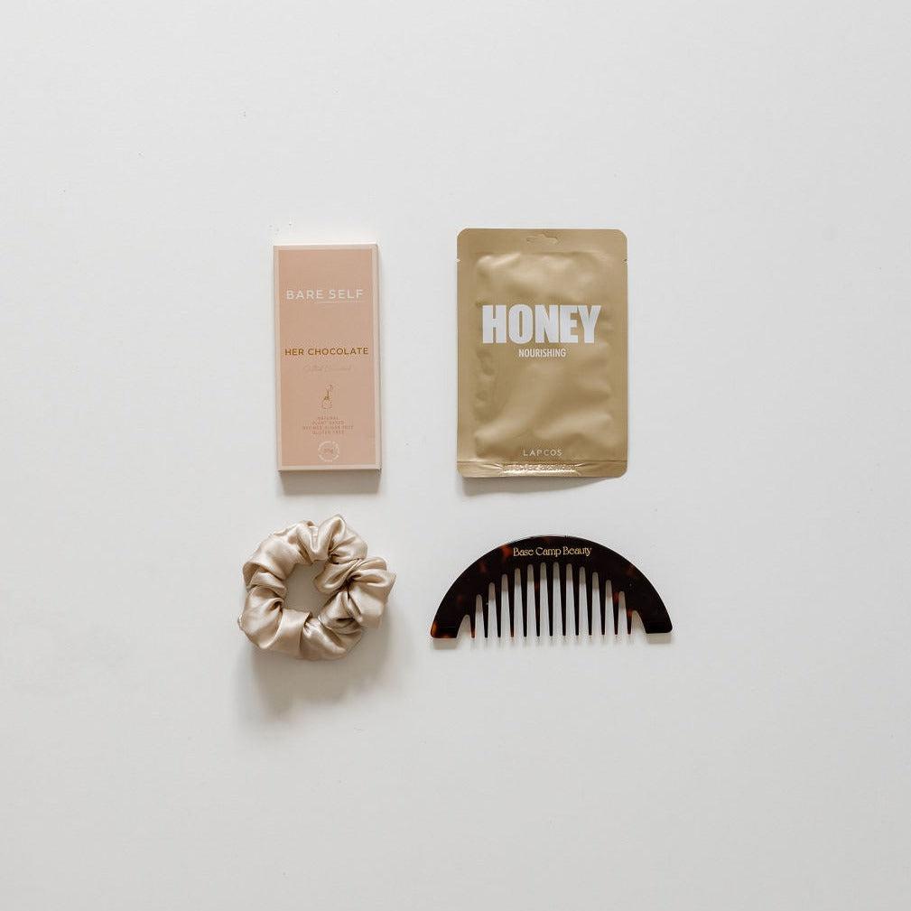 A biglittlegifting hair care kit with a little something comb and a bottle of honey.