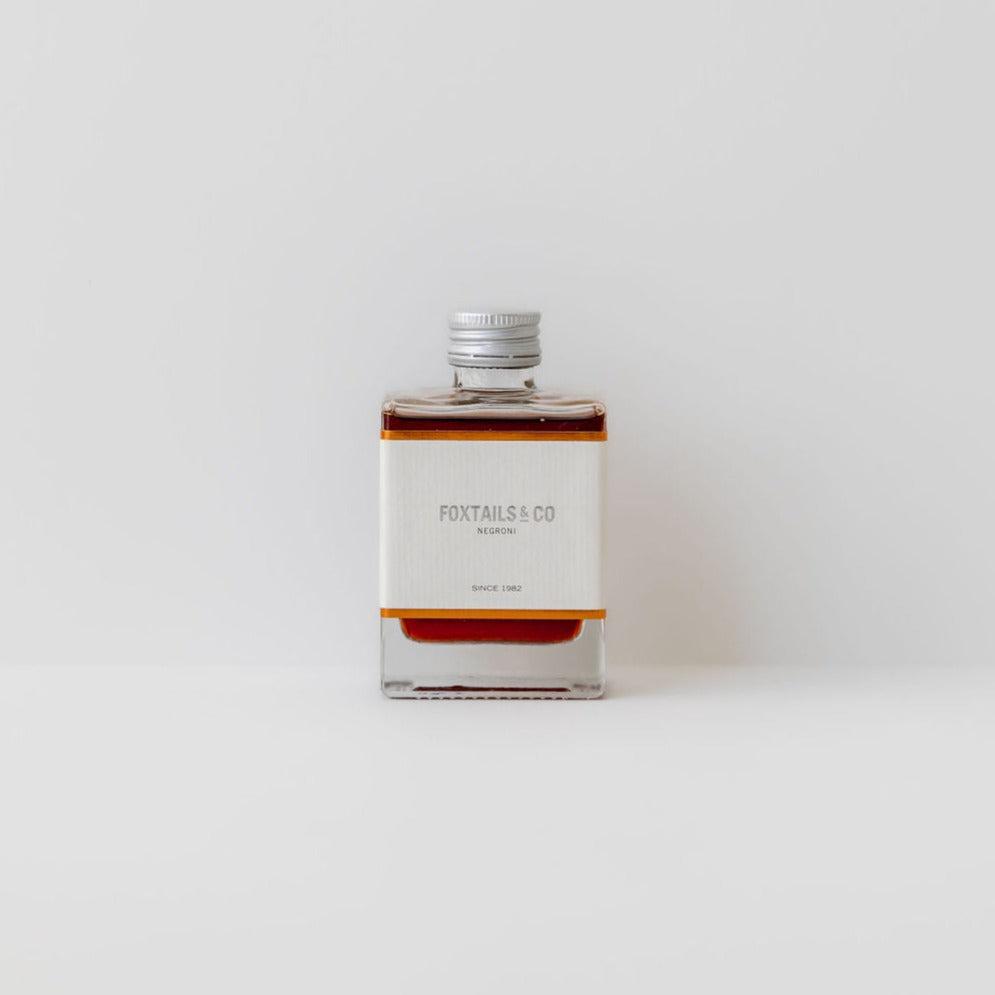 A bottle of Foxtails & Co negroni, a classic style gin cocktail with intense citrus flavors, sitting on a white surface.