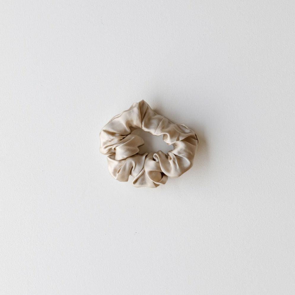 A champagne mulberry silk hair scrunchie from The Silk Collection placed on a plain white background.
