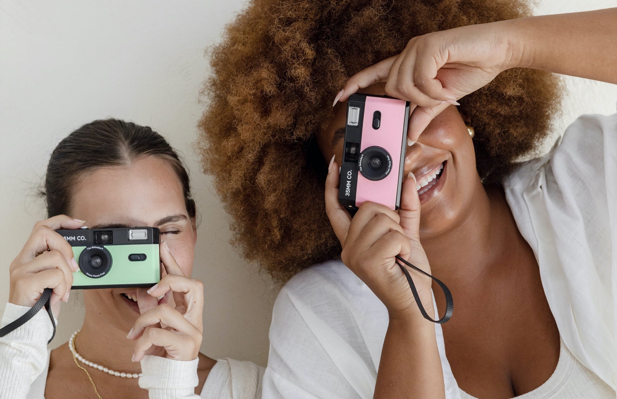 Two women are taking pictures of each other with polaroid cameras.