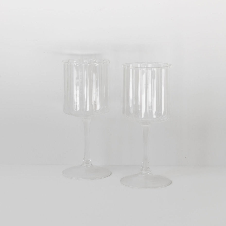 Two Fazeek wave wine glasses on a white surface.