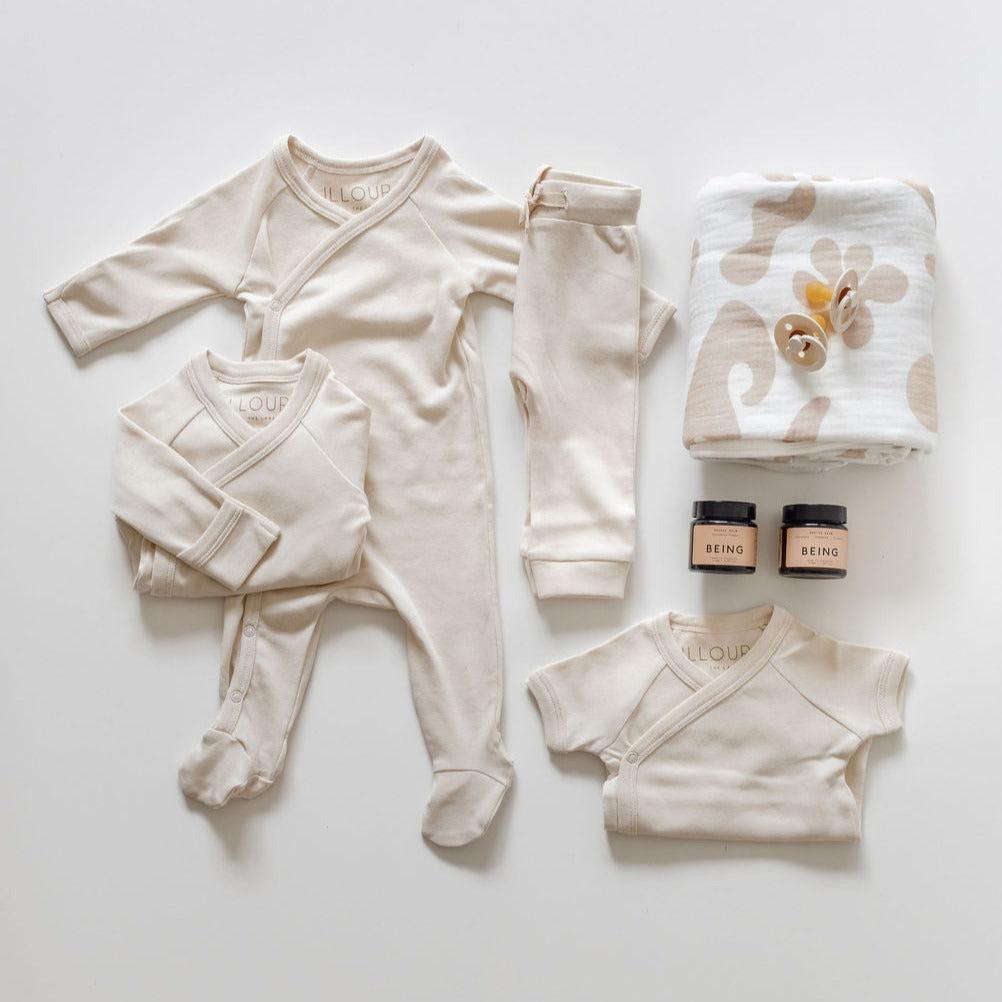 A set of biglittlegifting baby clothes and accessories laid out on a white surface.
