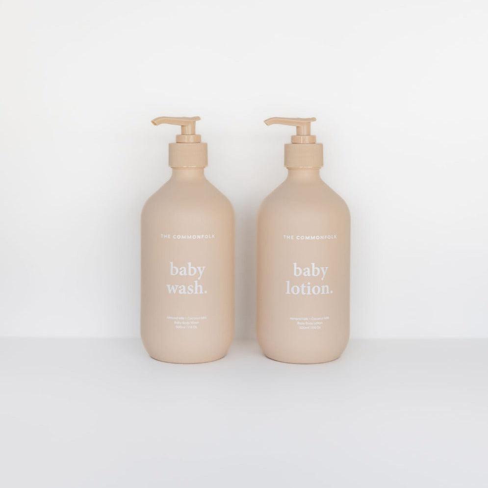 Two beige bottles labeled "The Commonfolk Collective Baby Hand + Body Wash" and "The Commonfolk Collective baby lotion," with pumps, against a white background.