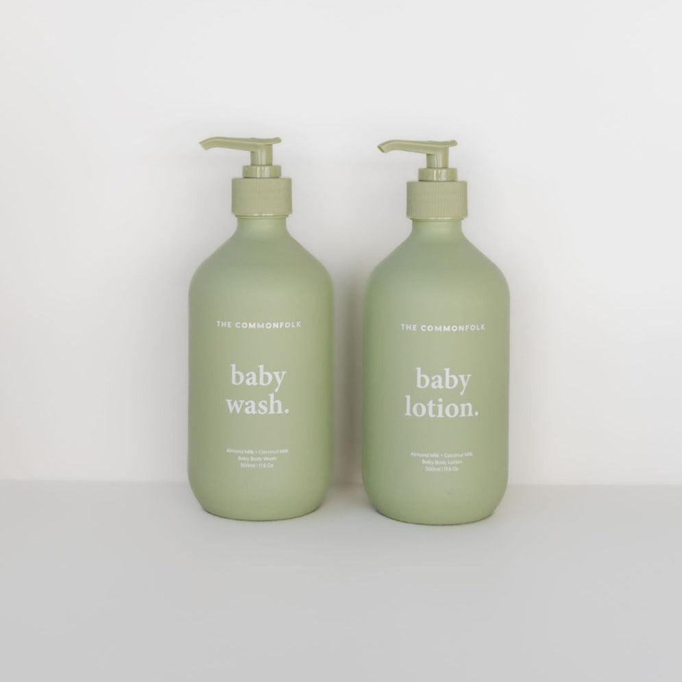 Two green bottles labeled "The Commonfolk Collective," one as "baby wash" and the other as "baby lotion," designed for sensitive skin, against a light gray background.