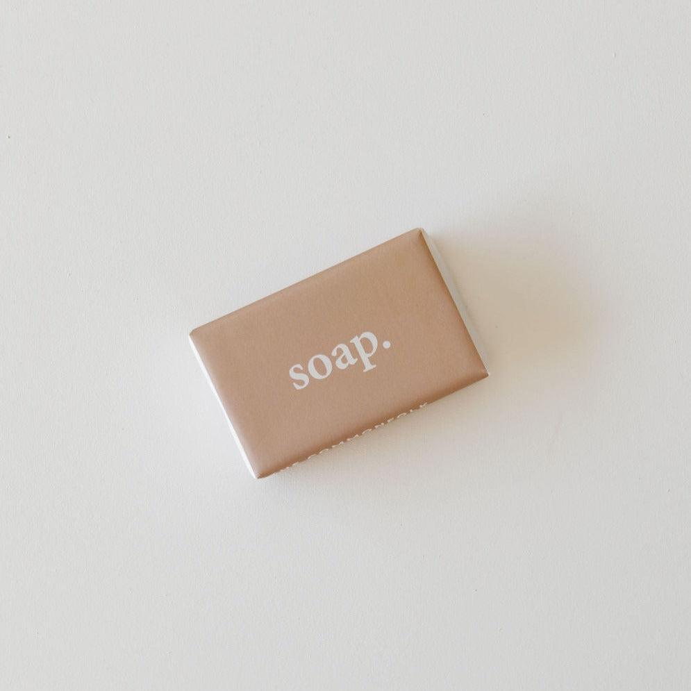 A body soap bar in minimalist packaging labeled "soap." on a plain white background, infused with natural vitamin E. | The Commonfolk Collective