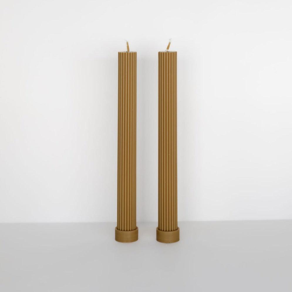 Two tall, beige Black Blaze column pillar candles standing upright on a white surface against a white background.