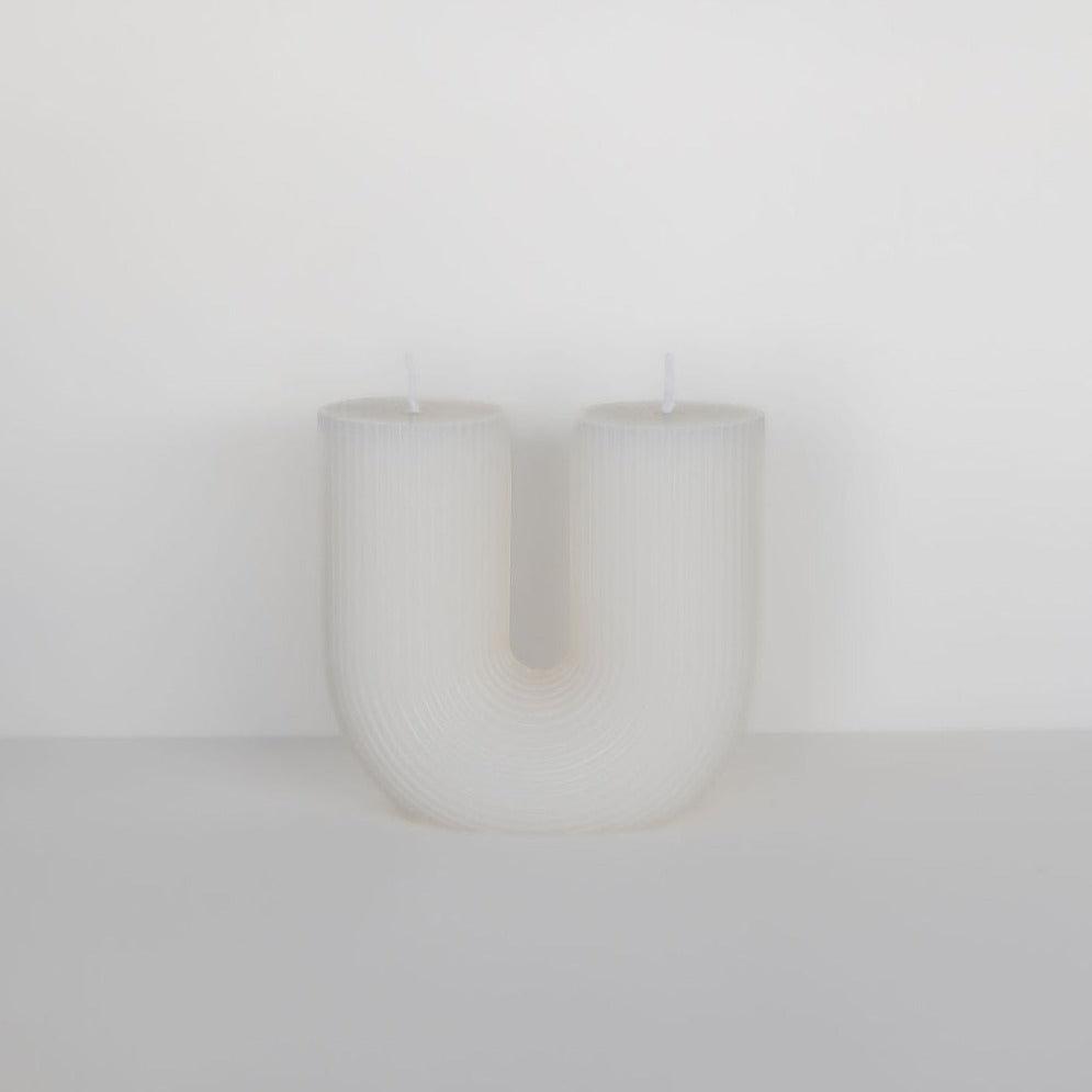 A white curl curl candle with the letter "u" on it in Black Blaze.
