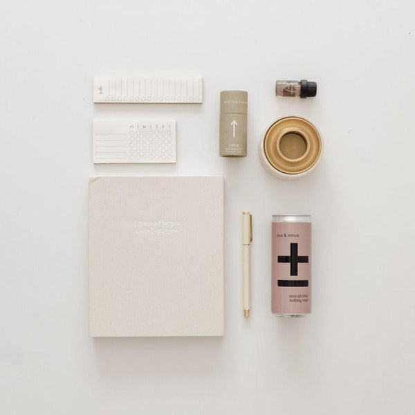 An entrepreneur vibes notebook, pen, and other items are laid out on a white surface.