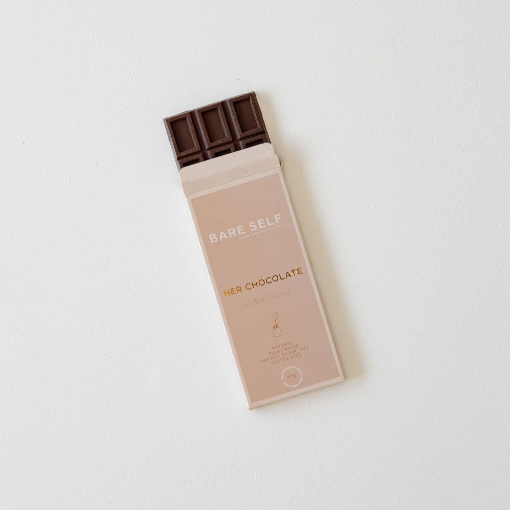 A her chocolate salted caramel bar sitting on a white surface. Brand: Bare Self.