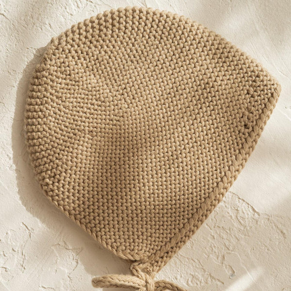 An Illoura the Label knitted beanie, the illoura baby bonnet in olive, made of organic cotton on a white surface.