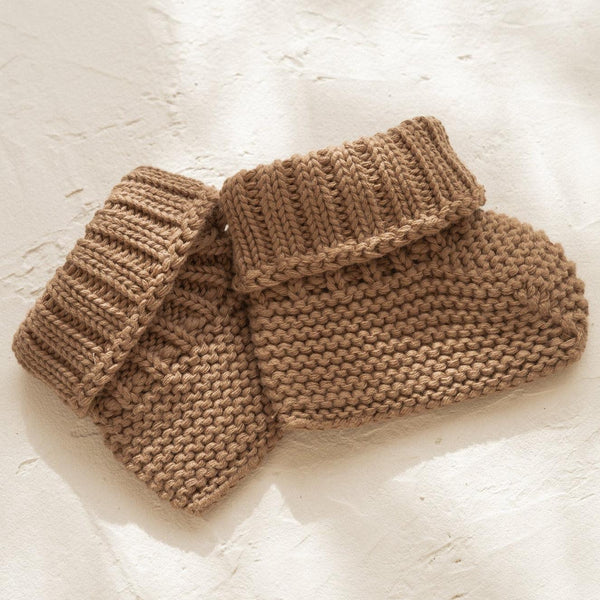 A pair of illoura baby booties made with organic cotton on a white surface.