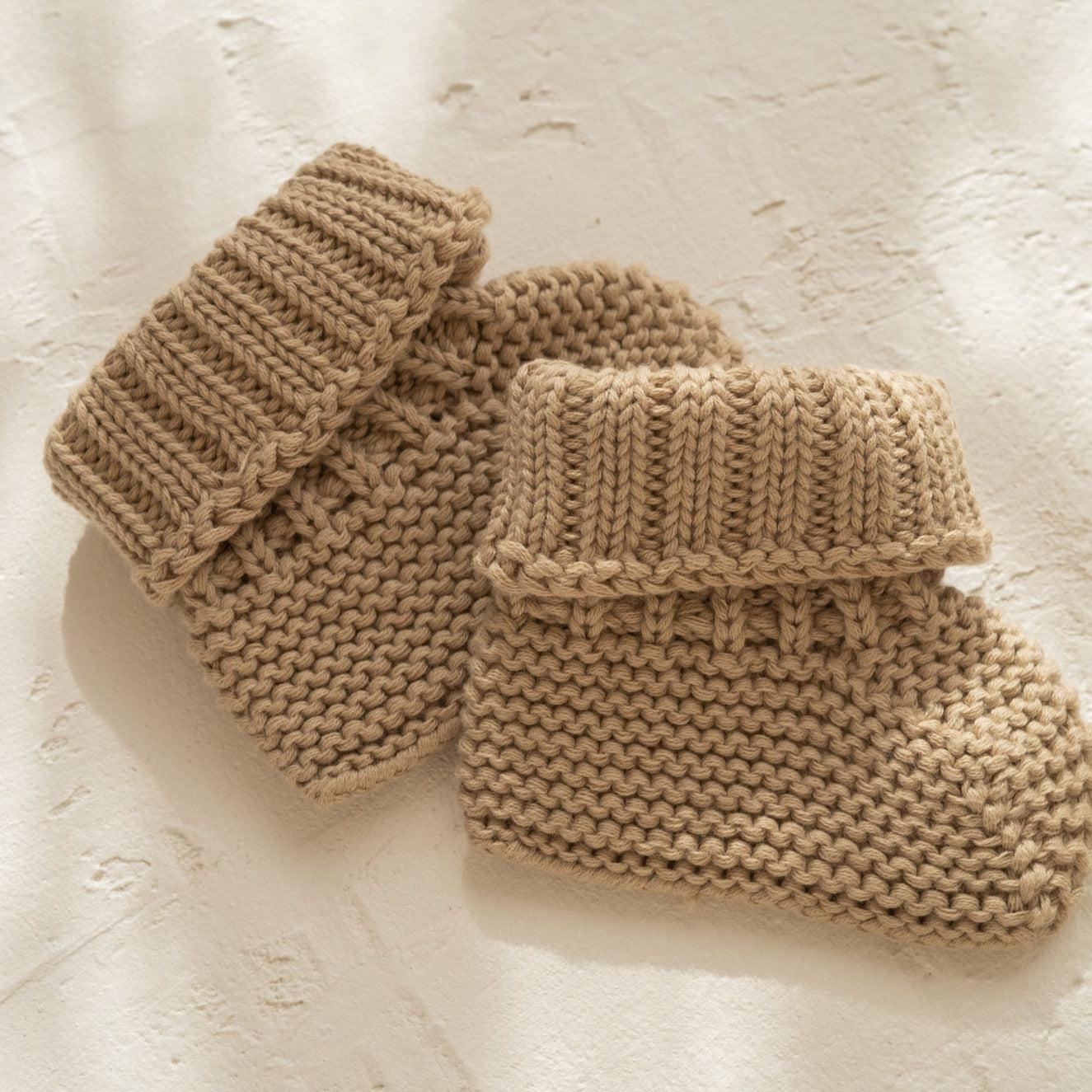 Two Illoura the Label organic cotton booties for babies on a white surface.