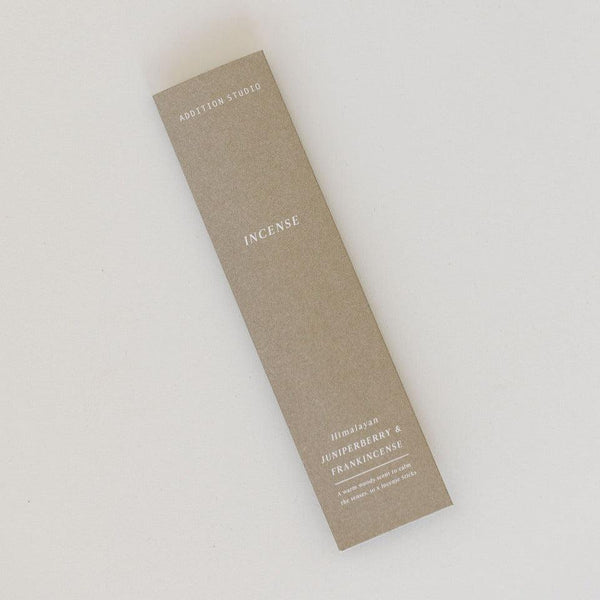 An Addition Studio juniperberry & frankincense incense stick on a white surface.