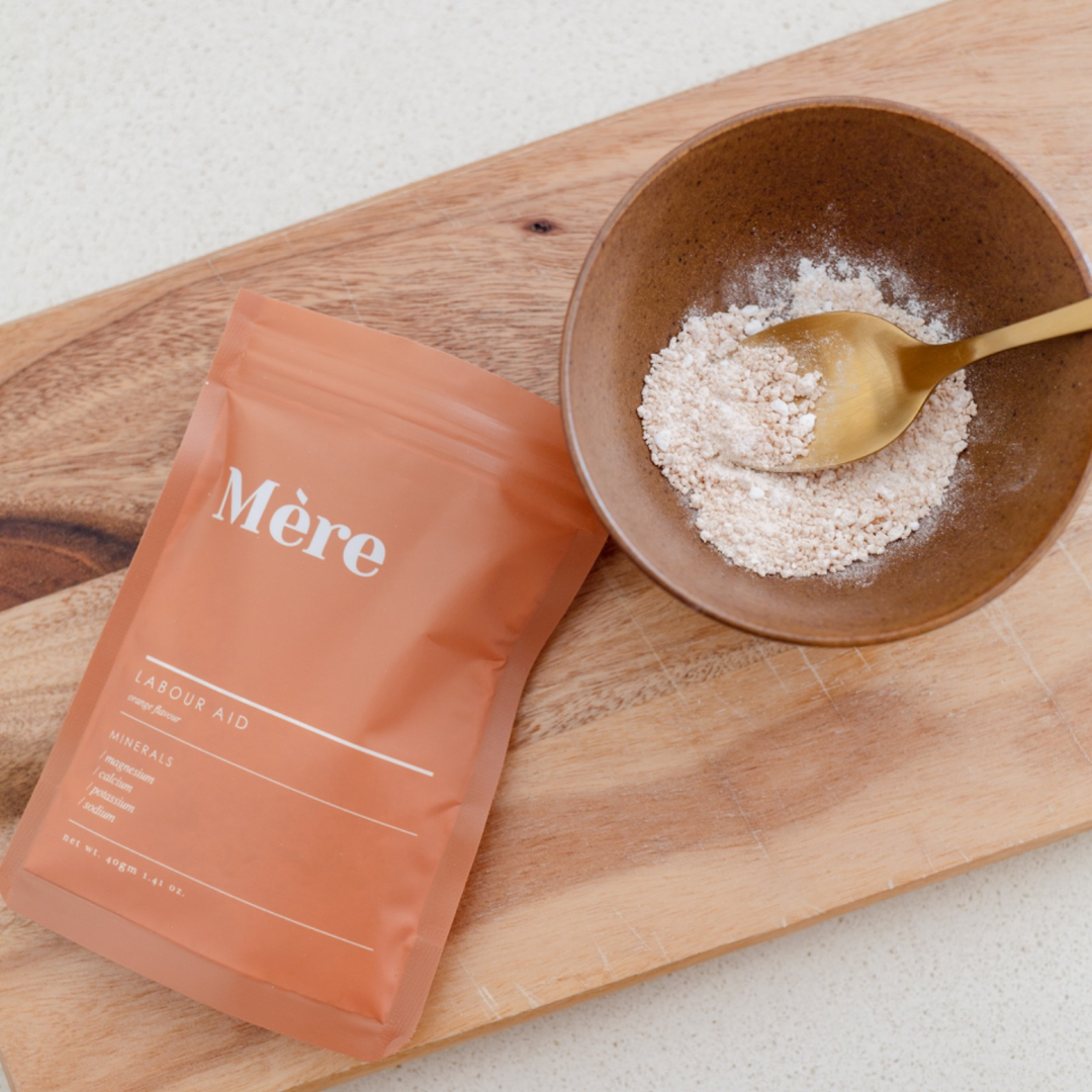 A bag of Labour Aid powder next to a wooden cutting board from Mère.