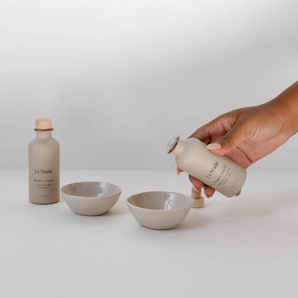 A hand is pouring a bottle of Le Marké tavola set into a bowl.