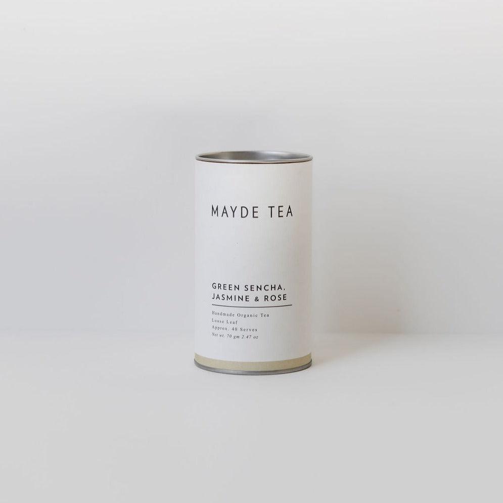 A cylindrical tin of Mayde Tea labeled "Mayde Tea Green Sencha, Jasmine & Rose" placed centrally against a plain white background.