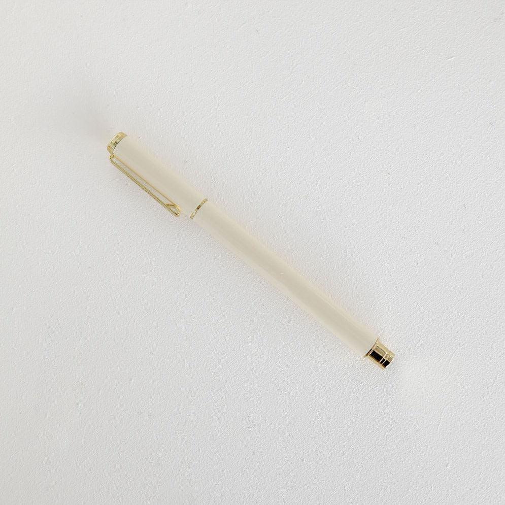 An Emma Kate Co metal rollerball pen with gold trim sitting on top of a white surface.