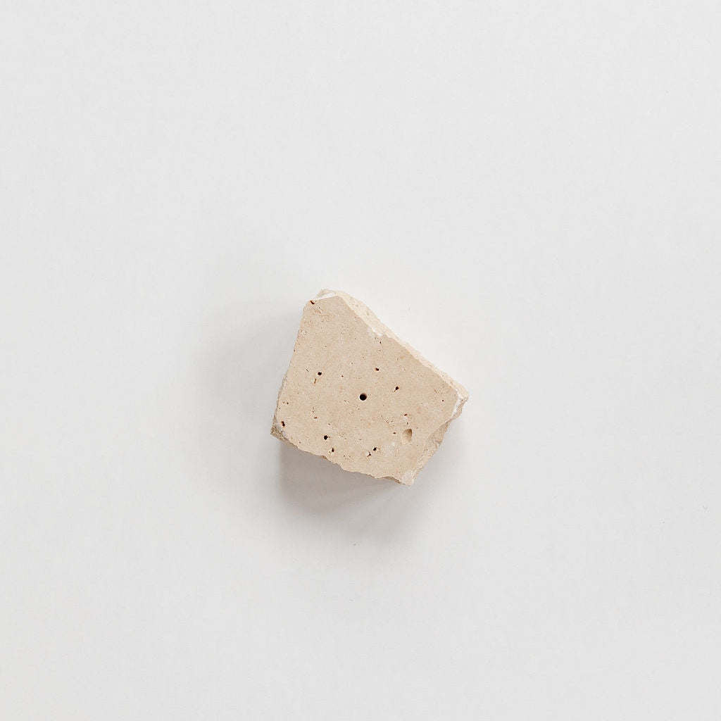 A small piece of Peggy Sue Co. Travertine Incense Holder on a white surface.