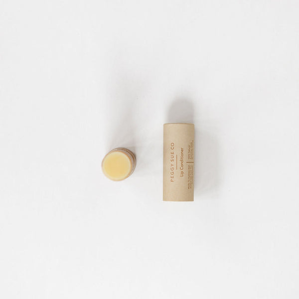 A small tube of Peggy Sue Co. Lip Conditioner, a hydrating lip balm, sitting on a white surface.
