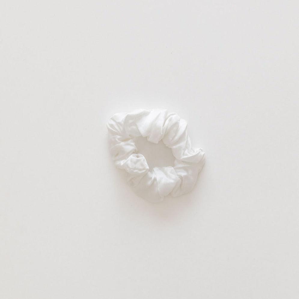 The Silk Collection pearl white silk hair scrunchie on a plain, light background.