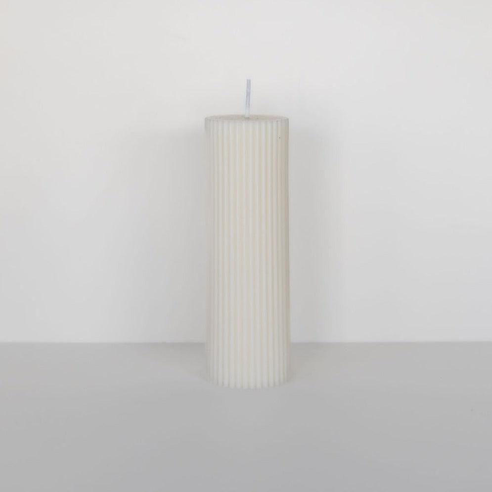 A wide column pillar candle from Black Blaze sitting on a white surface.