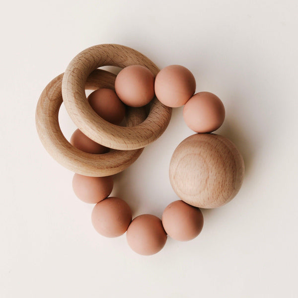 Wooden Silicone Teethers and spheres interspersed with brown eggs on a white background by Dove & Dovelet.