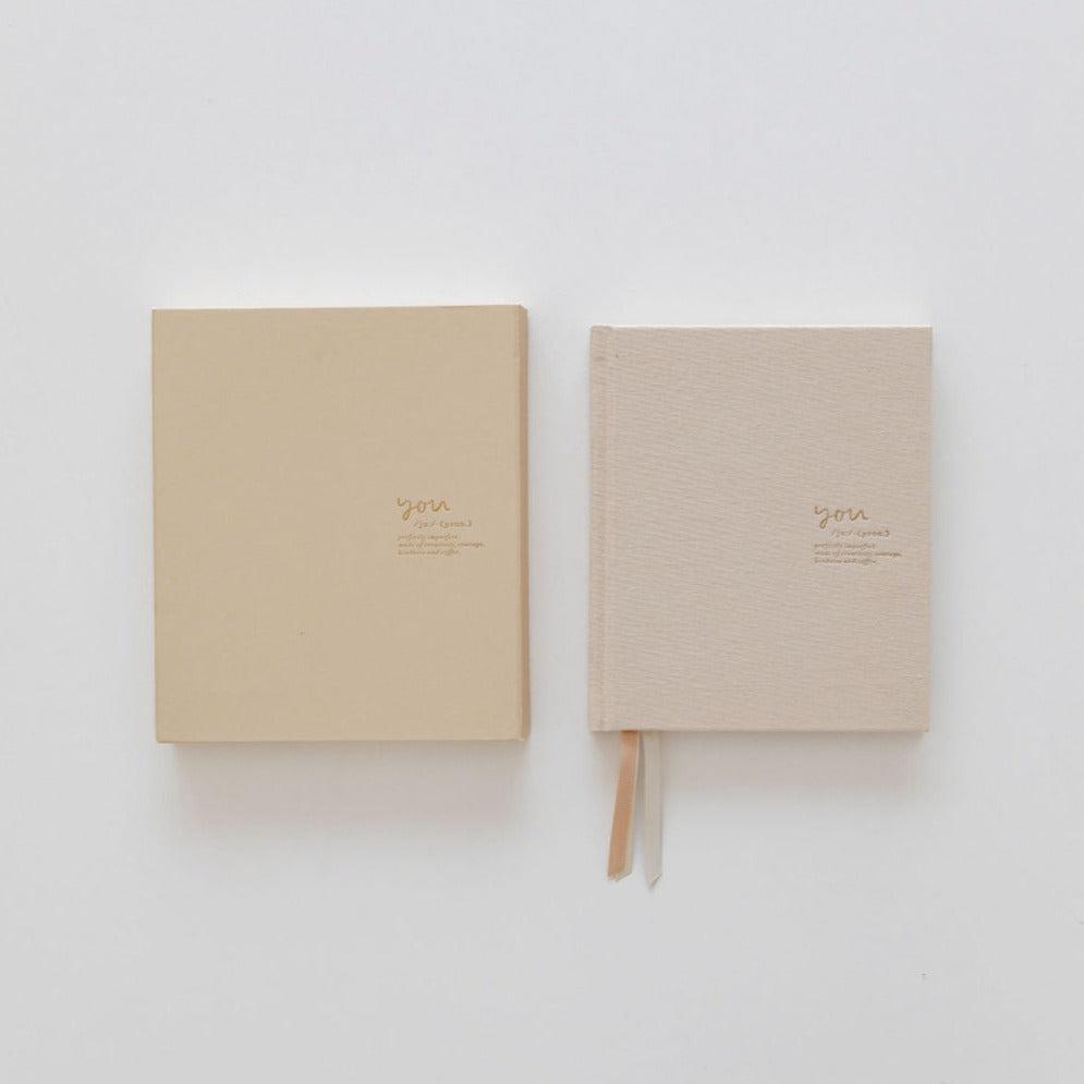 Two beige Emma Kate Co hardcover journals on a white surface.