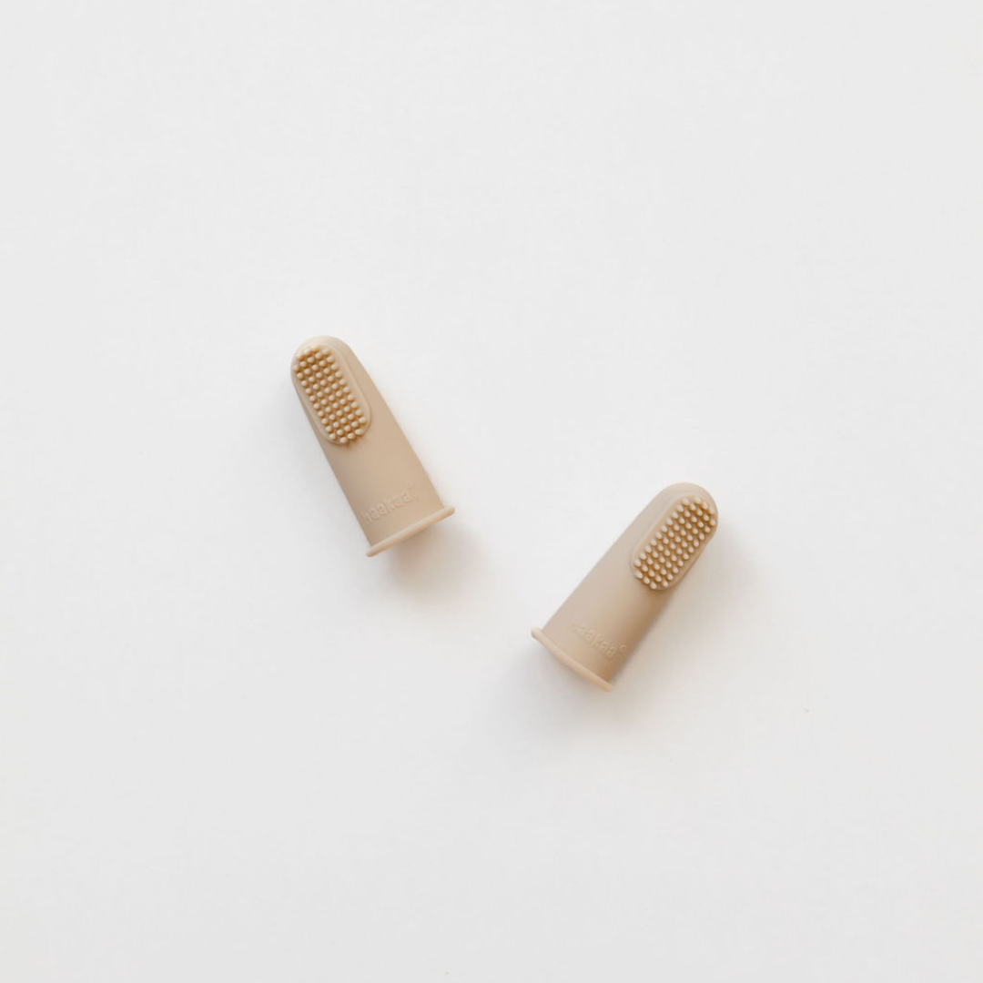 A pair of Haakaa Silicone Finger Toothbrush | 2pk earplugs made of beige plastic on a white surface.